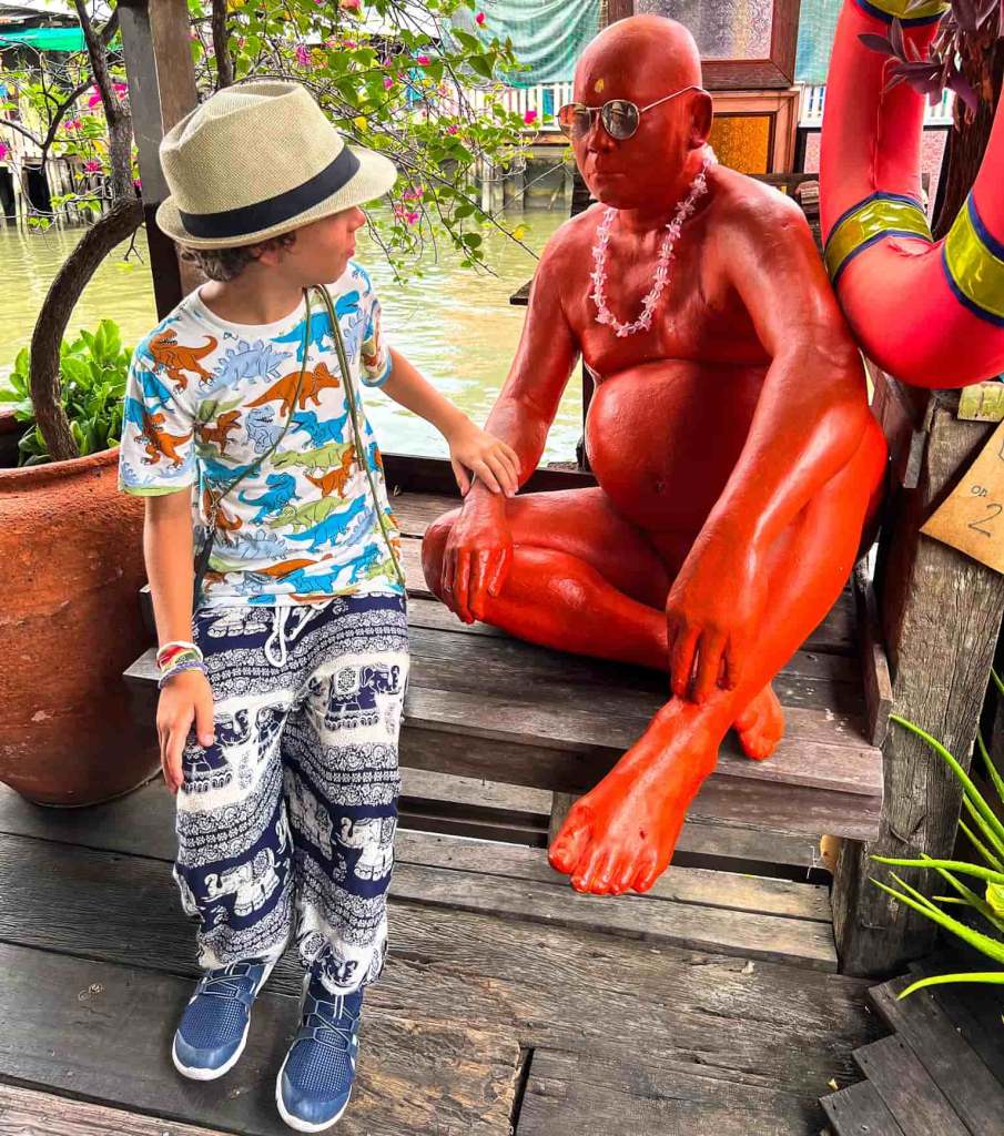 Bambino ammira statua di un uomo alla Artist House nei canali di Donburi a Bangkok