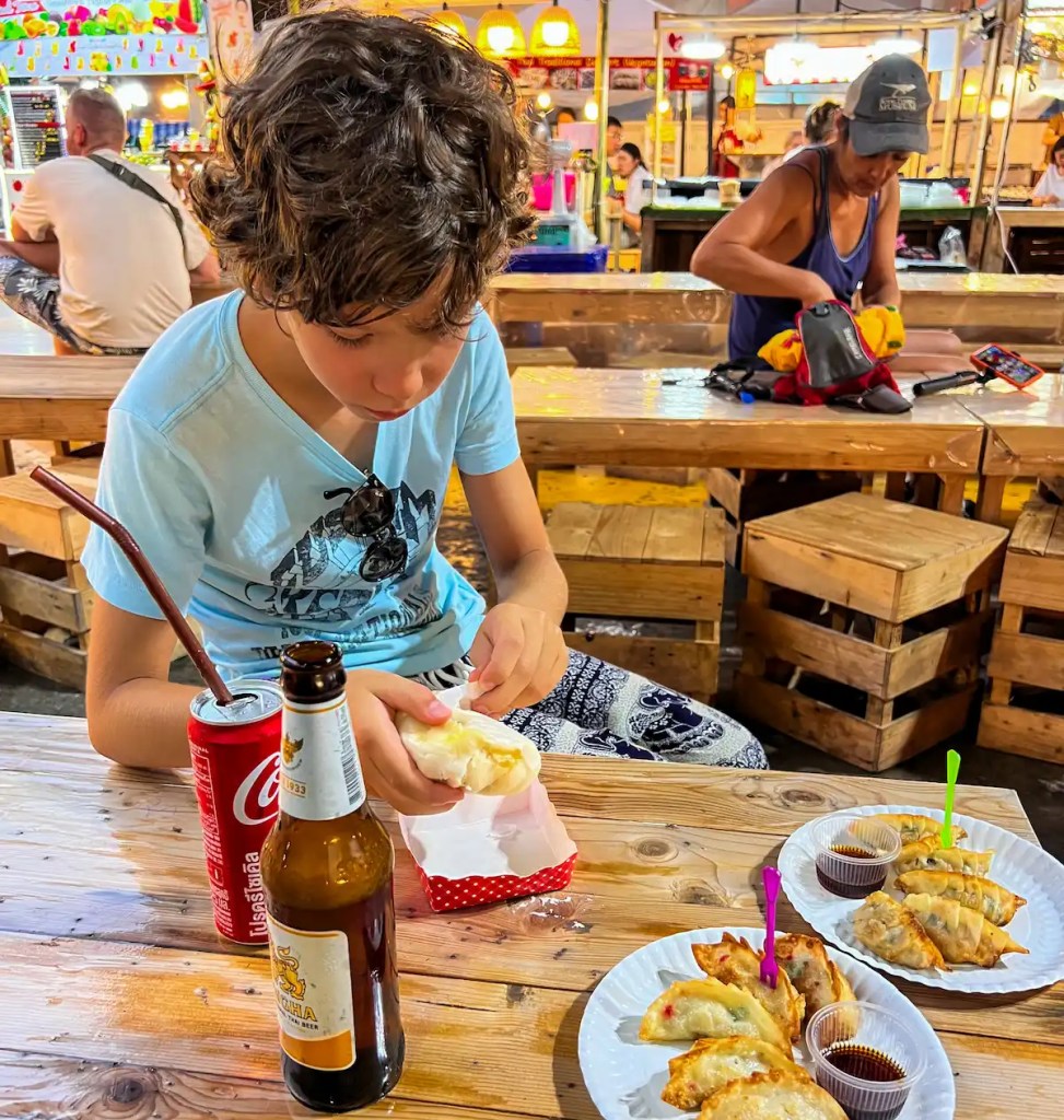 Bambino mangia in un mercato locale in Thailandia